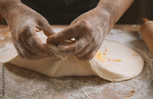 Fototapeta Naklejka Na Ścianę i Meble -  Hands of a woman kneading dough on a wooden table