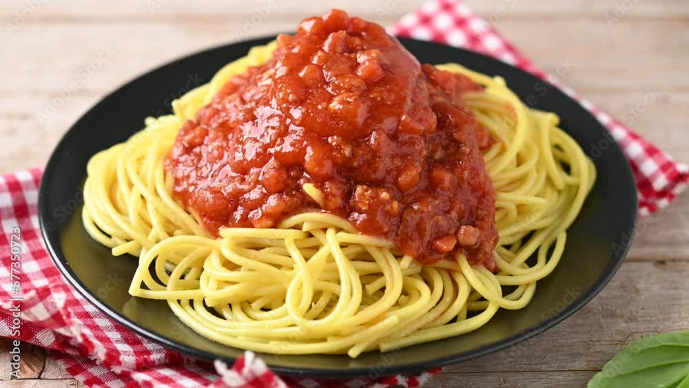 Pouring bolognese sauce and cheese on spaghetti plate on wooden table. Pouring bolognese sauce and cheese on spaghetti plate on wooden table.
