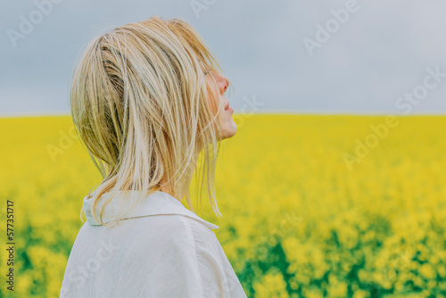 Beautiful blonde in white shirt on yellow rapeseed field