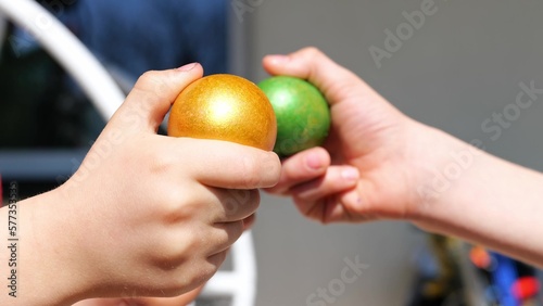 Obraz na płótnie Two kind beat colorful green and orange Easter eggs outdoor. Seasonal tradition games in happy Easter holiday. Close up. Knocking eggs figh game. w salonie