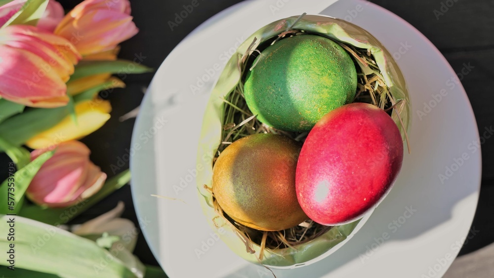 Easter colorful eggs rotate in nest with hey outdoor in sunny warming day.