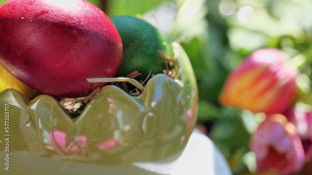 Easter colorful eggs rotate in nest with hey outdoor in sunny warming day.
