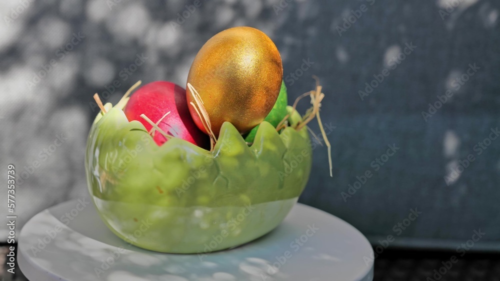 Easter colorful eggs rotate in nest with hey outdoor in sunny warming day.