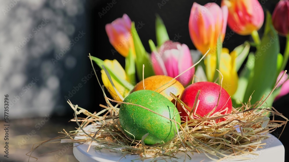 Easter colorful eggs rotate in nest with hey outdoor in sunny warming day.