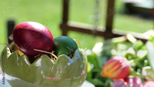 Easter colorful eggs rotate in nest with hey outdoor in sunny warming day.