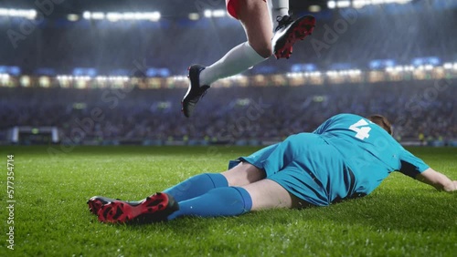 Aesthetic Shot of Red Team Soccer Football Player Successfully Avoiding Sliding Tackle From Opponent on Stadium With Fans Cheering. Super Slow Motion Captures Dangerous Moment During Championship.