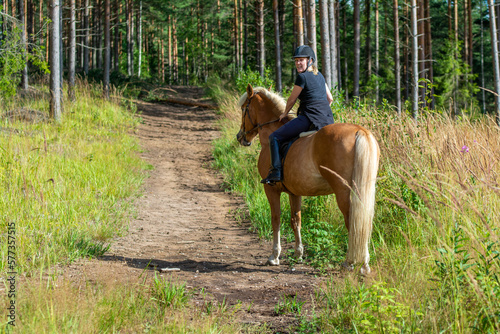 Woman horseback riding in forest trail © citikka
