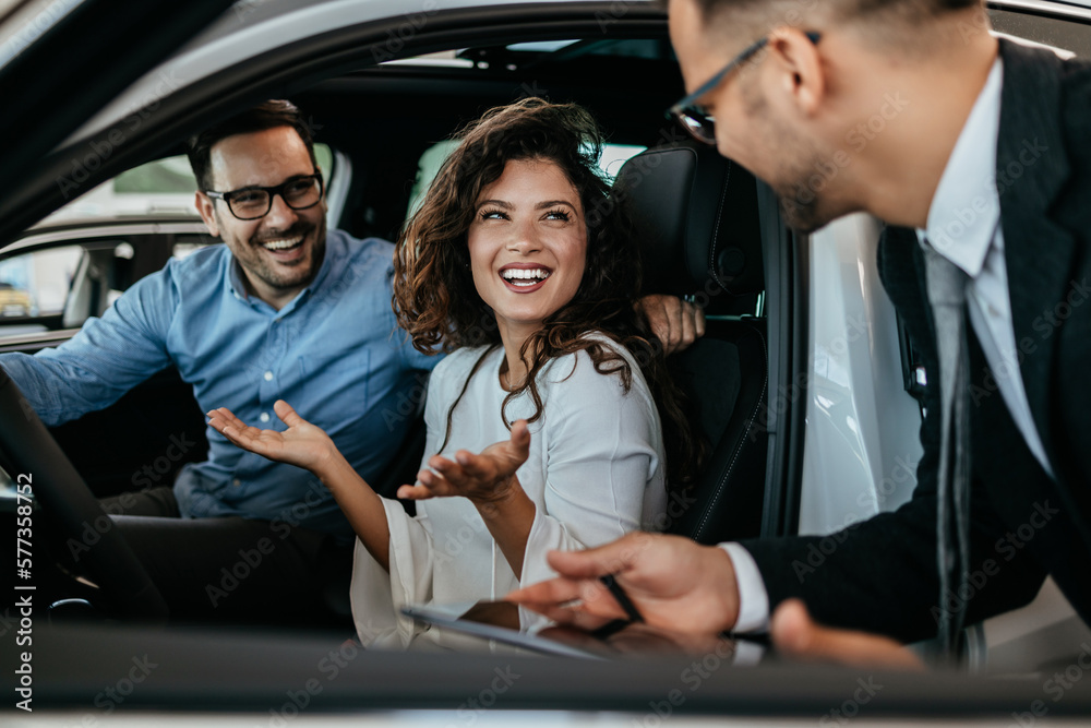 Middle age couple choosing and buying car at car showroom. Car salesman helps them to make right decision. Middle age couple choosing and buying car at car showroom. Car salesman helps them to make right decision.