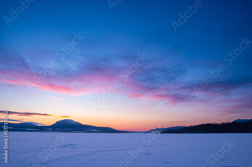 氷に覆われた湖から見る鮮やかな夜明けの空。日本の北海道の屈斜路湖