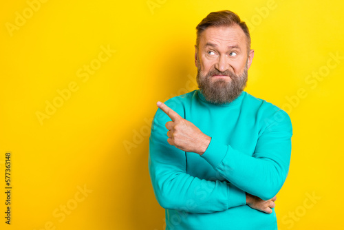 Photo of dissatisfied man wear trendy clothes arm demonstrate empty space bad news information isolated on yellow color background