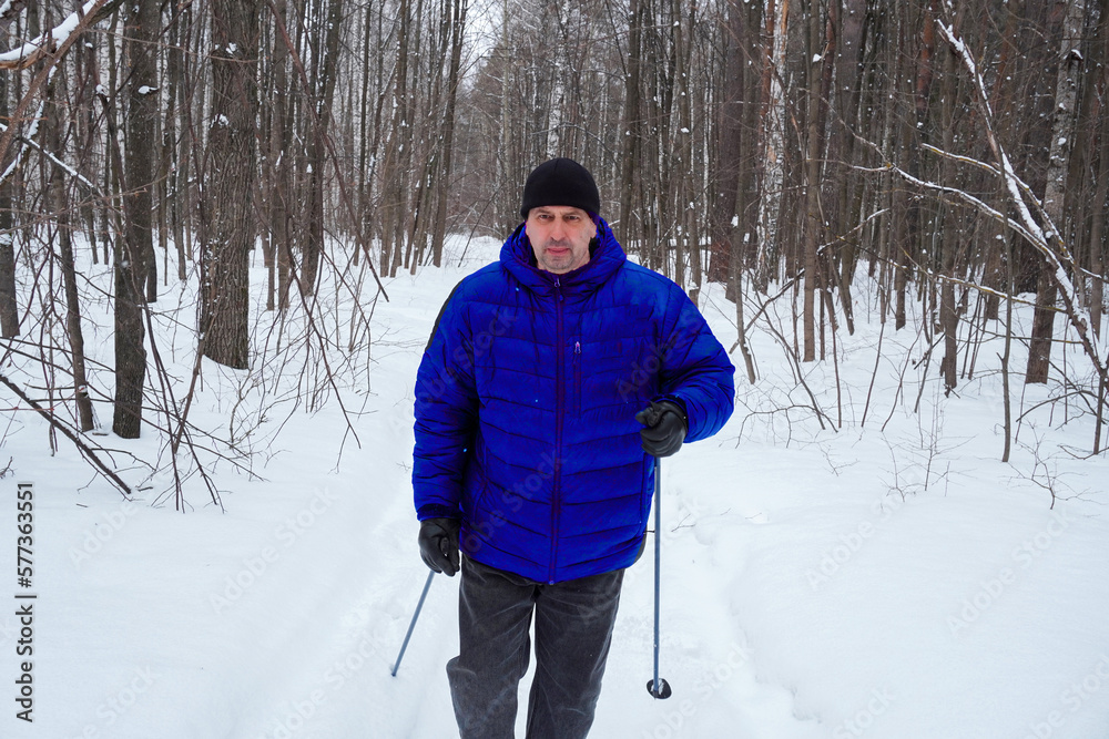 man 50 years old skiing in the forest in winter