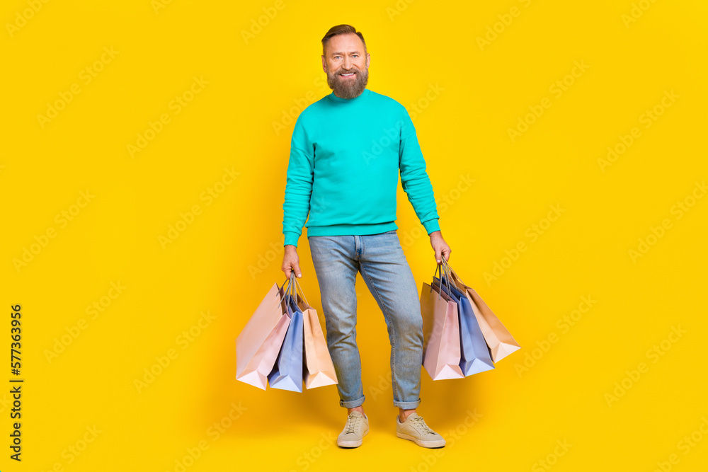 Full body photo of attractive grandpa shopping bags enjoy black friday wear trendy aquamarine outfit isolated on yellow color background Full body photo of attractive grandpa shopping bags enjoy black friday wear trendy aquamarine outfit isolated on yellow color background