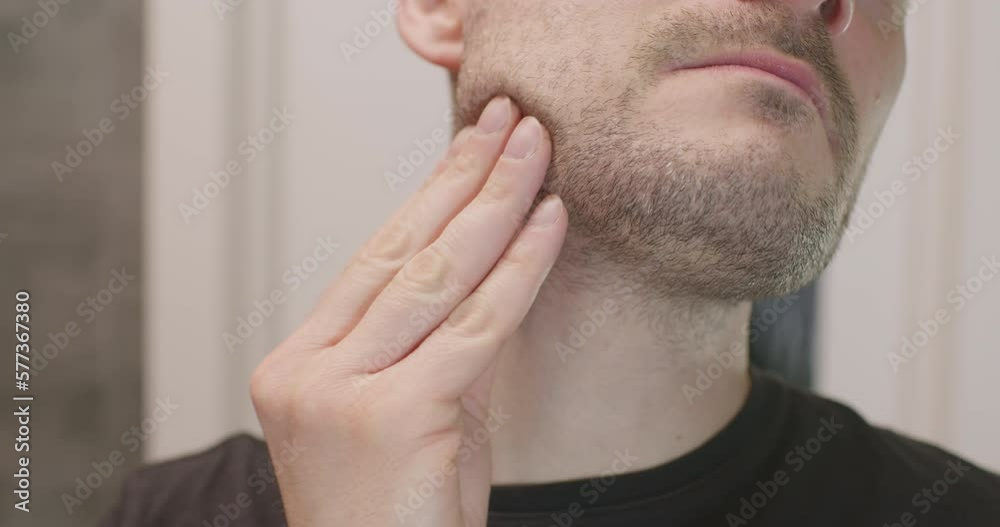 Handsome unshaven man looking into the mirror in bathroom Handsome unshaven man looking into the mirror in bathroom