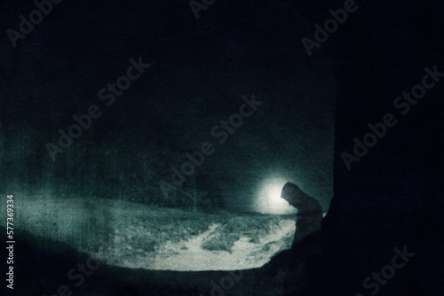 A superntaural concept of a transparent hooded ghostly figure. Silhouetted on the edge of a tunnel. On a spooky night. With a grunge, blurred edit.