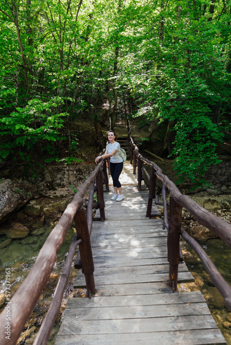 a woman with a backpack stands on a wooden bridge walking in the woods hiking journey