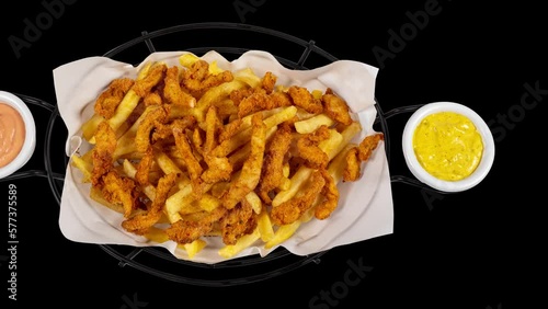 Crispy chicken pieces with cajun spice on french fries accompanied by cocktail sauce