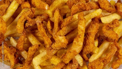 Crispy chicken pieces with cajun spice on french fries accompanied by cocktail sauce