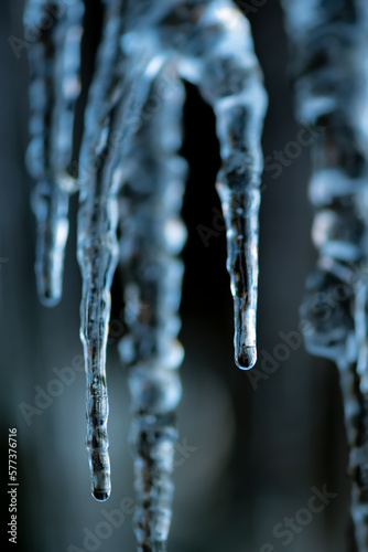 Icicles with clear water drops at a creek cascade waterfall on a very cold winters day in Sauerland Germany. Close up macro of transparent and translucent turquoise blue shapes with blurred background © ON-Photography