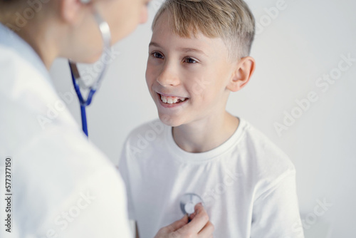 Doctor and happy smiling child boy patient at usual medical inspection in clinic. Medicine, healthcare concepts.