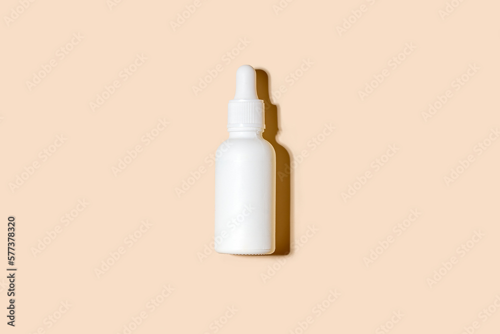 White cosmetic bottles with dropper on pastel beigh background. Shadow White cosmetic bottles with dropper on pastel beigh background. Shadow