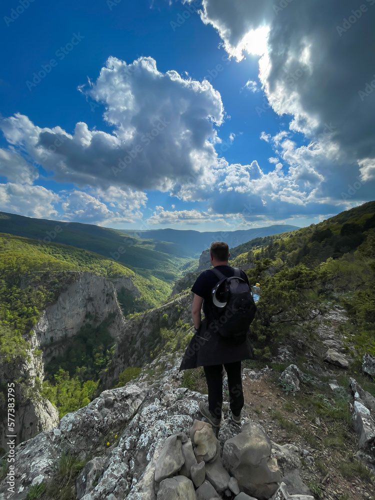 a man stands on a mountain and looks at nature hiking journey