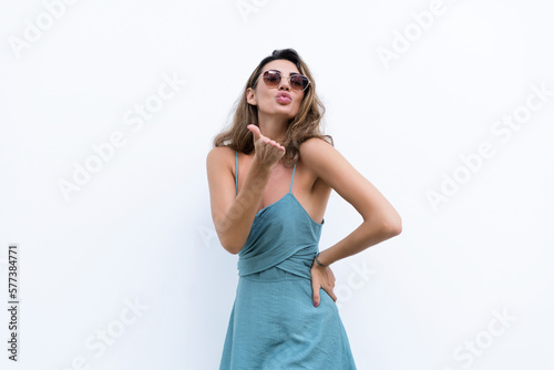 Portrait of beautiful woman in green fitting summer dress on white background natural day light, wearing sunglasses, smiling excited