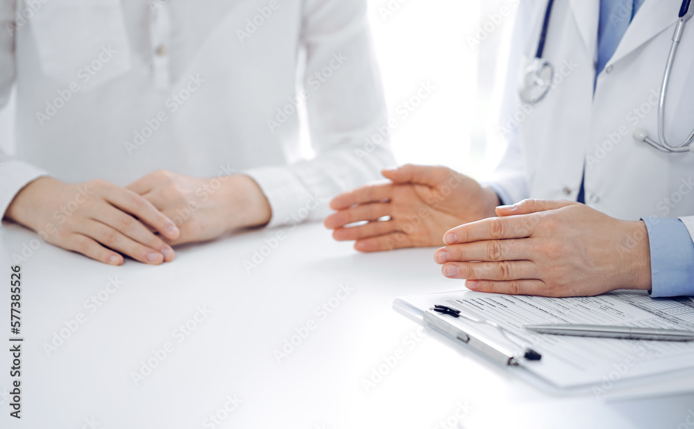 Doctor and patient discussing current health questions while sitting near of each other at the table in clinic, just hands closeup. Medicine concept. Doctor and patient discussing current health questions while sitting near of each other at the table in clinic, just hands closeup. Medicine concept.