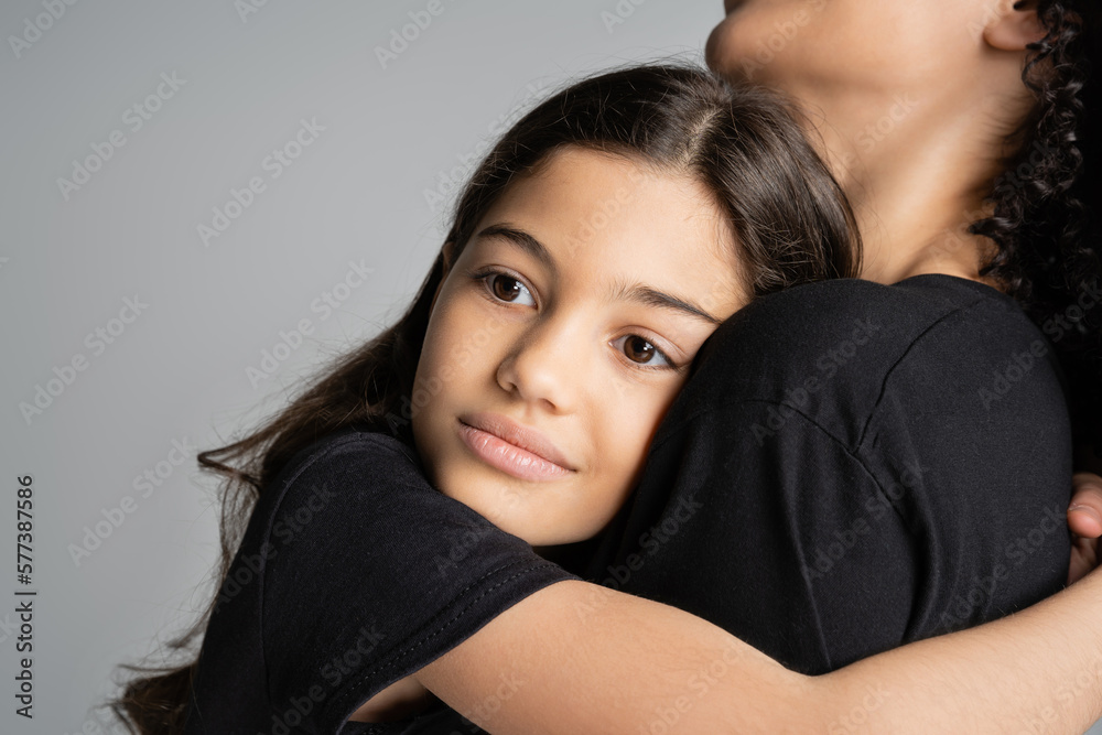 Preteen kid hugging mother in black t-shirt isolated on grey. Preteen kid hugging mother in black t-shirt isolated on grey.