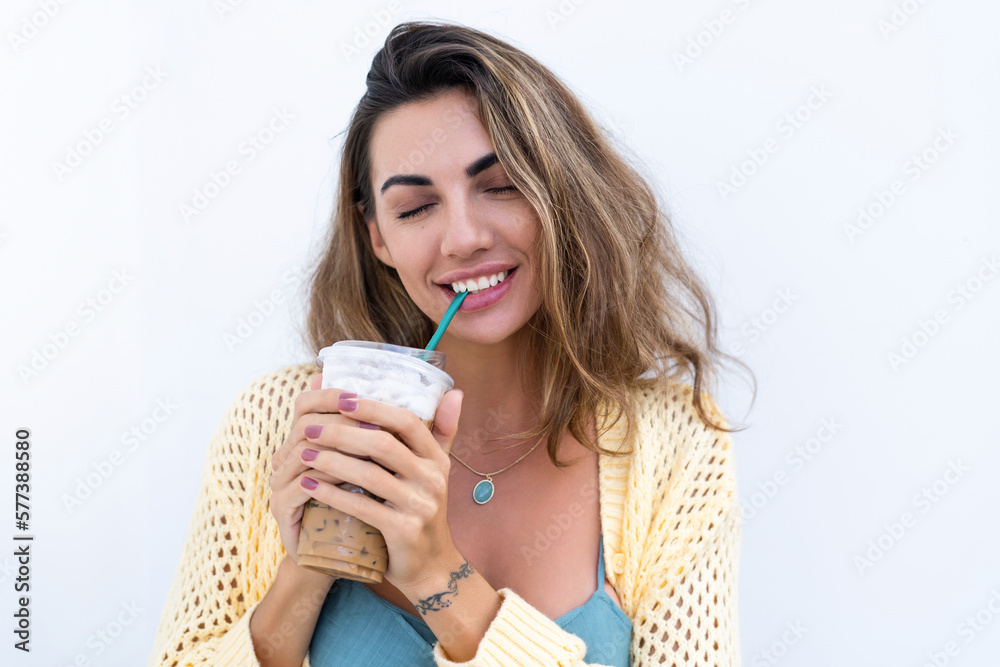 Portrait of beautiful woman in green summer dress on white background natural daylight, holding iced coffee cappuccino happy smiling excited Portrait of beautiful woman in green summer dress on white background natural daylight, holding iced coffee cappuccino happy smiling excited