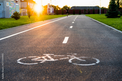 bike path with sunset sun, bicycle sign on asphalt