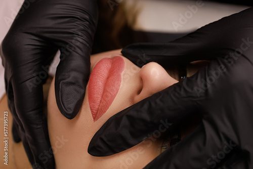 permanent lip makeup finished work after the procedure, the master holds the lips of the model