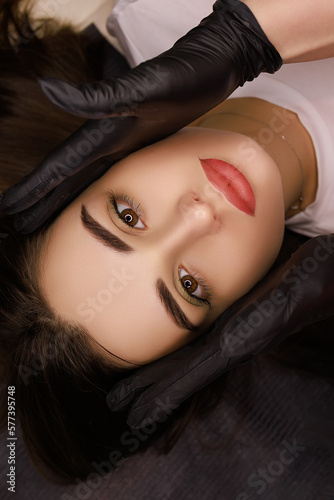 You fool permanent lip makeup master turns model's head to show permanent lip procedure photo