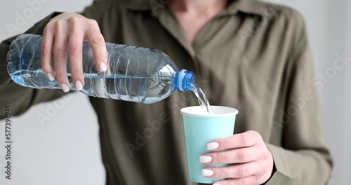 Woman pouring mineral water from plastic bottle into glass closeup 4k movie slow motion photo