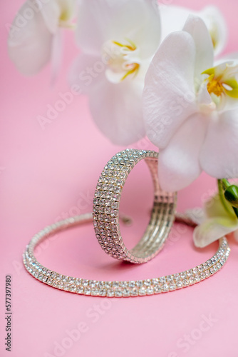 Bracelet and necklace and white orchid on pink background 