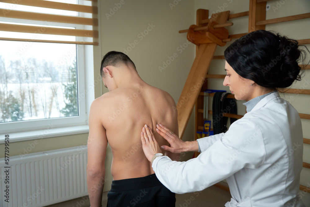 Young doctor neurologist examining her patient. Pretty female orthopedist with patient in her office. Neurologist checks the reflexes of a ypung age male patient. Young doctor neurologist examining her patient. Pretty female orthopedist with patient in her office. Neurologist checks the reflexes of a ypung age male patient.