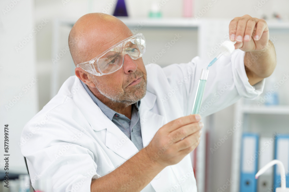 male researcher holding dropper and test tube male researcher holding dropper and test tube