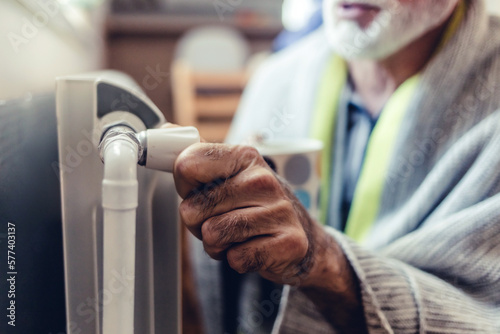 Men's hand adjusting thermostat valve of heating radiator in the bedroom. Senior men adjusting the knob of heating radiator.