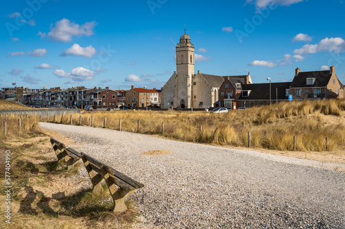 Dutch seaside resort Katwijk aan Zee, church seen from the pedestrian path with benches along sand dunes photo