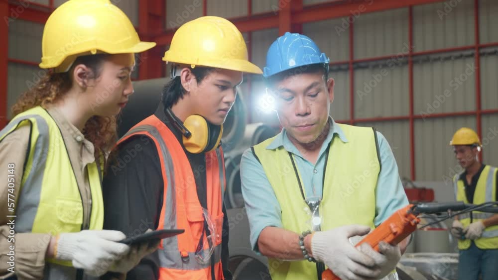 Supervisor senior man training controlling overhead crane with remote new worker in manufacturing, Engineering team use remote control panel for lifting down power trolley crane in factory warehouse