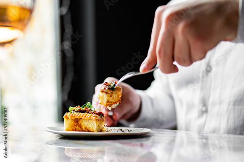 man hands with fork and knife eating brioche with salmon mousse in cafe