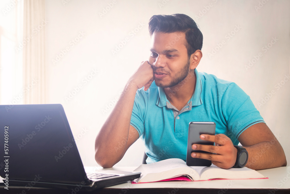 Smiling man having video calling on phone with laptop Smiling man having video calling on phone with laptop