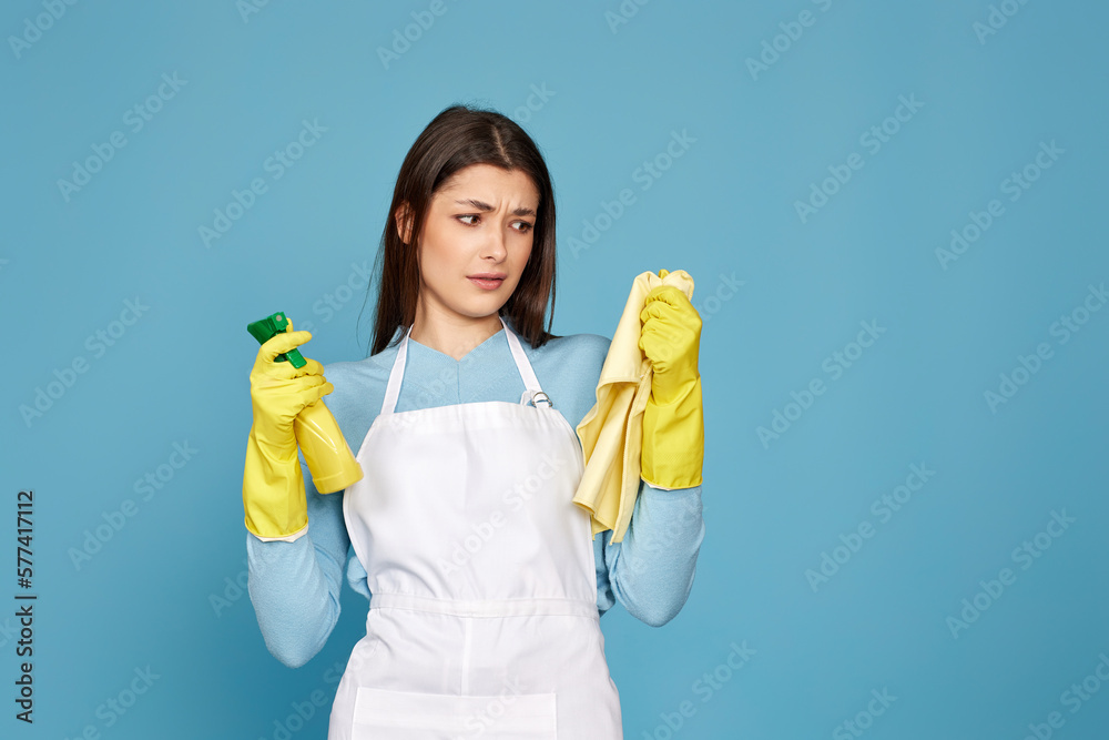 frowning woman cleaner apron with cleaning rag and detergent sprayer frowning woman cleaner apron with cleaning rag and detergent sprayer