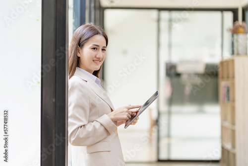 Attractive Asian female worker standing in her office with digital tablet, finance work concept