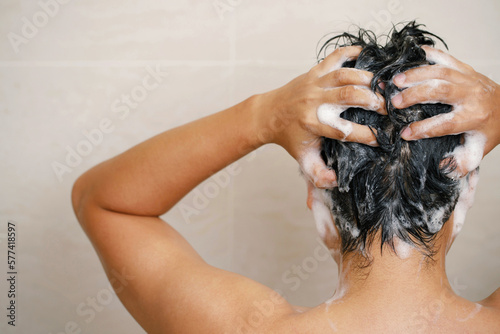 A man is washing his hair with shampoo
