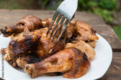 Closeup of a fork picking up a piece of chopped Lechon Manok, or roasted chicken served outside. photo