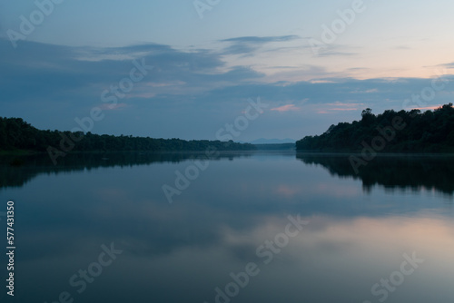 Landscape of cloudy twilight with symmetric reflection on water surface, distant mountain in haze
