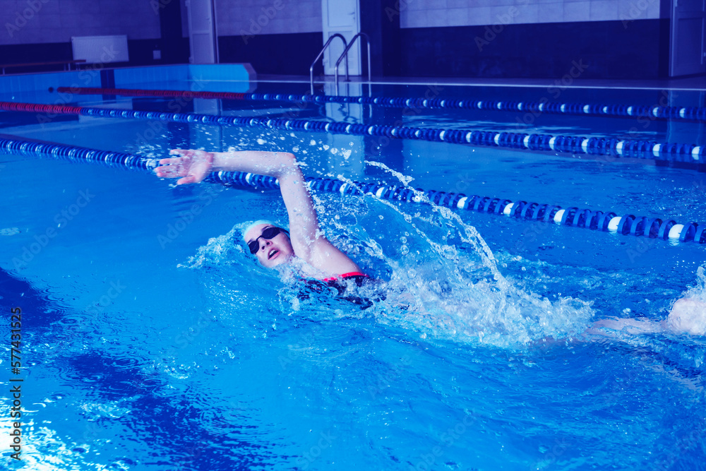 Female swimmer racing in the pool. A professional athlete overcomes stress and adversity in the pool.