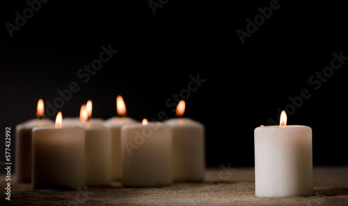 bullying concept, composed by group of lit candles, on sand with black night background