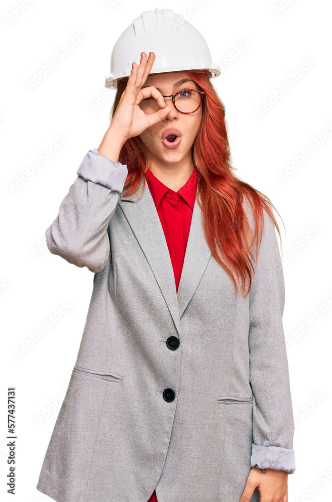Young redhead woman wearing architect hardhat doing ok gesture shocked with surprised face, eye looking through fingers. unbelieving expression. Young redhead woman wearing architect hardhat doing ok gesture shocked with surprised face, eye looking through fingers. unbelieving expression.