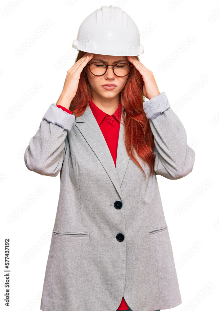 Young redhead woman wearing architect hardhat with hand on head for pain in head because stress. suffering migraine.